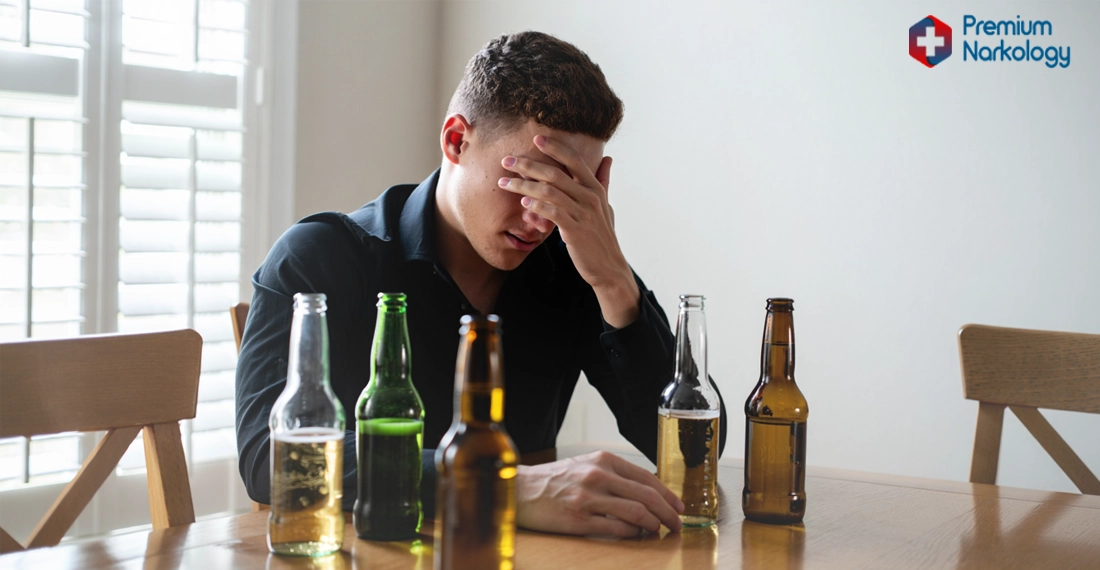 Грустный мужчина за столом с пустыми бутылками