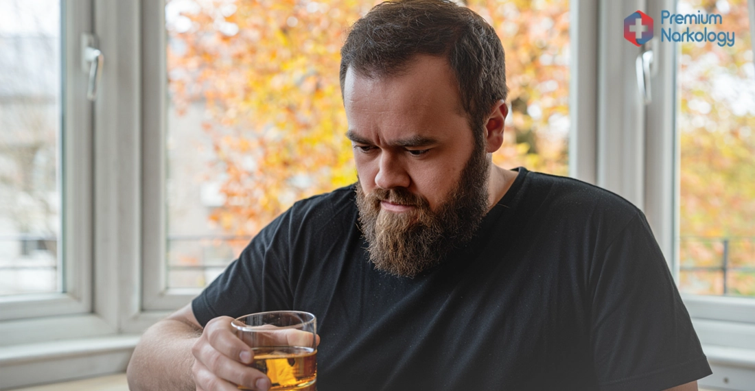 Мужчина со стаканом алкоголя у окна