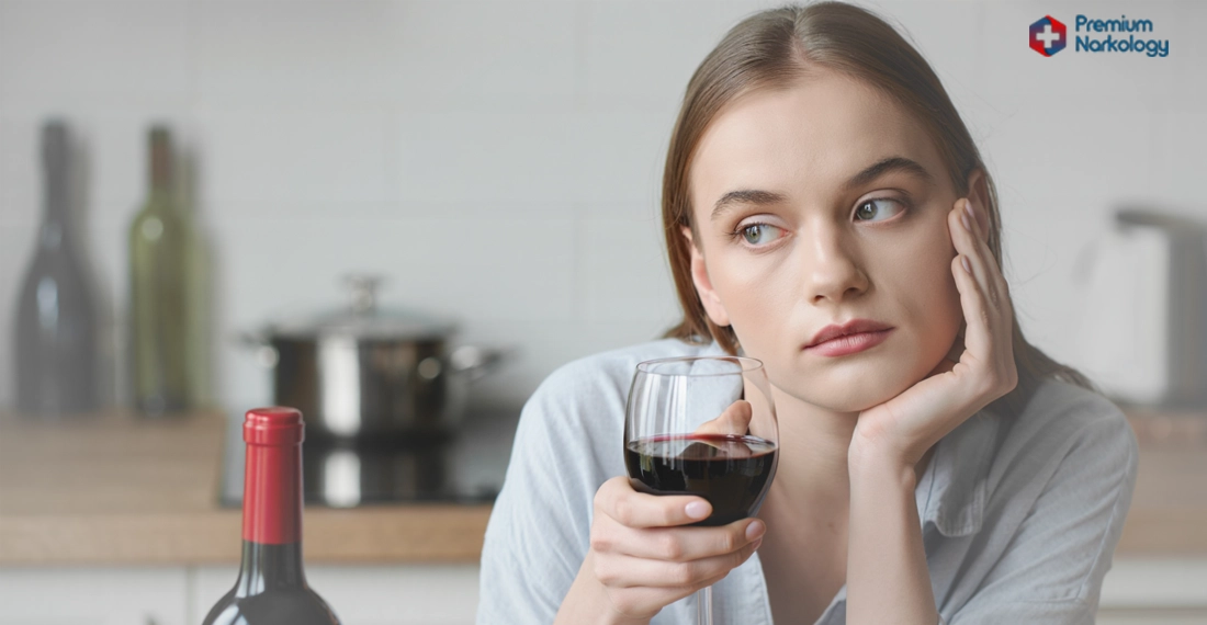 Женщина сидит с бутылкой вина и бокалом