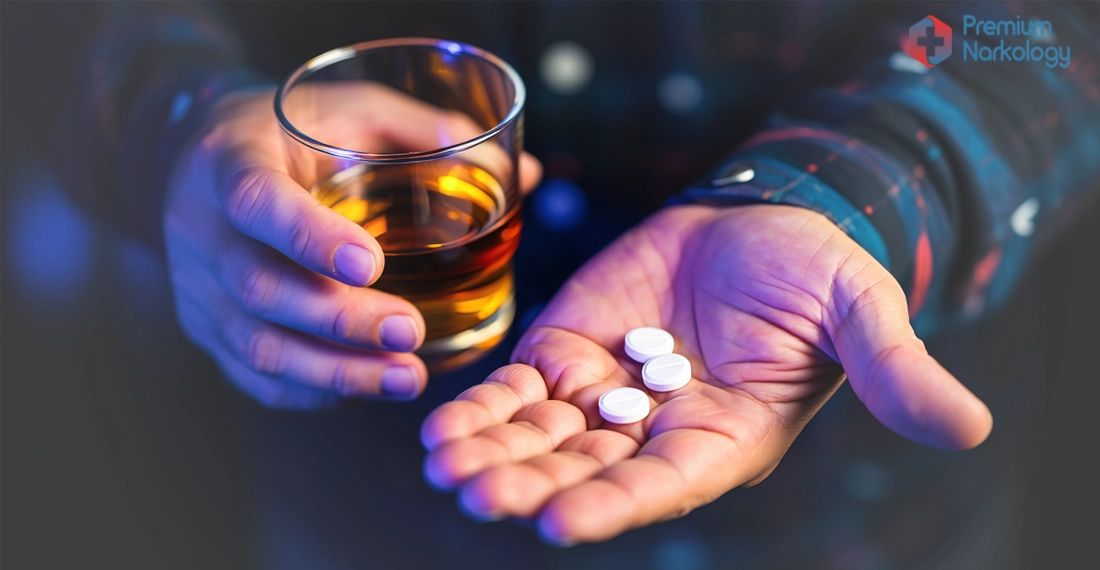 Женщина держит в руках стакан с алкоголем и таблетки